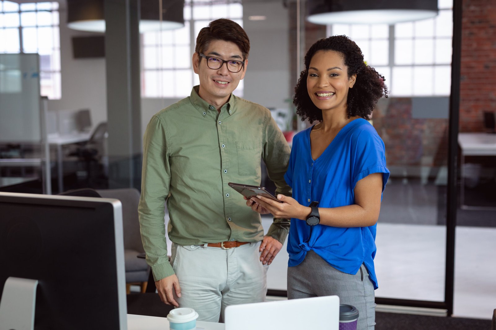 Portrait of diverse male and female colleague holding tablet and smiling standing in office. working in business at a modern office.